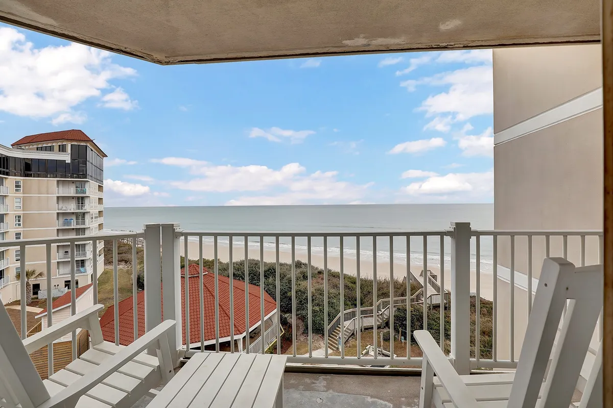 Balcony chairs arranged to overlook a breathtaking expanse of ocean and sky, with gentle clouds drifting above the water. The scene radiates relaxation, perfect for savoring morning coffee or watching a glowing sunset.